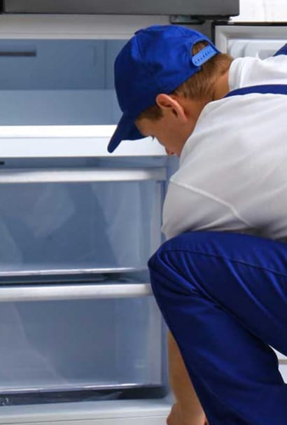 A technician fixing a freezer to prevent it from failing and ensure proper cooling.