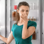 A person placing baking soda inside a refrigerator to remove odors.